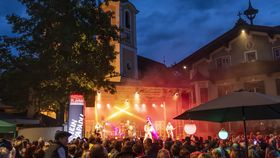 Auf einer Freiluftbühne, des nachts auf einem Dorfplatz, findet ein Lichterspektakel vor einer Menschenmenge statt