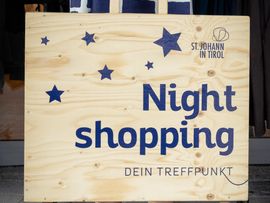 Eine Frau hält eine große Shoppingtüte mit der Aufschrift 'Night Shopping' in der Hand