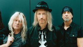 Fünf Männer stehen vor einer türkisen Wand und schauen in die Kamera