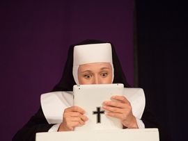 Eine Nonne tippt auf einem Ipad, auf dem ein Kreuzsticker klebt