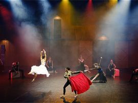 Mehrere Tänzer auf belebter Bühne und Scheinwerfer