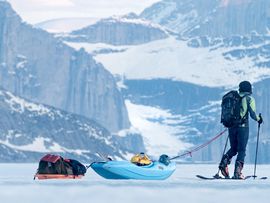 Langläufer zieht auf einem zugefrorenem See einen Schlitten hinter sich her