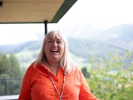 Ute Baues auf einer Terrasse mit Berglandschaft im Hintergrund.