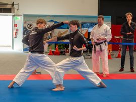 Zwei Karate-Sportler demonstrieren Techniken auf einer Präsentationsfläche vor Publikum.