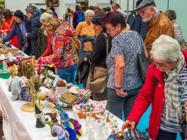 Besucherinnen und Besucher sitzen bei der SenAktiv-Messe zusammen und unterhalten sich.