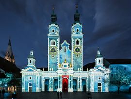 Kirchenfassade mit blauer Lichtinszenierung vor Nachthimmel