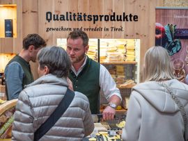 Besucher informieren sich an einem Stand mit regionalen Qualitätsprodukten aus Tirol.