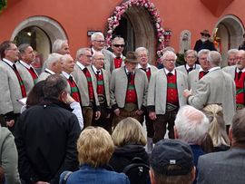Männer in Trachten stehen auf einem Platz und singen