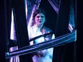 Junge Schauspielerin auf Theaterbühne mit sorgenvollem Blick