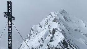 Verschneite Tiroler Bergspitze mit Gipfelkreuz