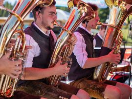 3 Blasmusiker beim Spielen auf einer Almhütte