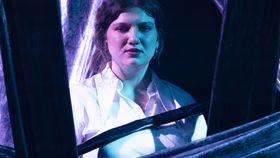 Junge Schauspielerin auf Theaterbühne mit sorgenvollem Blick 