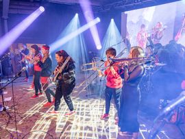 Mehrere Frauen spielen Blasinstrumente auf Bühne bei Konzert