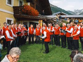 Männerchor in roten Westen singt im Freien.