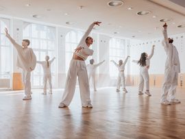 Tänzer in weißer Kleidung in einem Saal