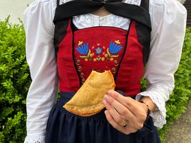 Frau im Dirndl, die einen Krapfen vor sich hält