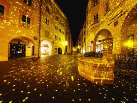 Altstadt-Platz mit gelbem Lichtspiel auf Häuserfassade