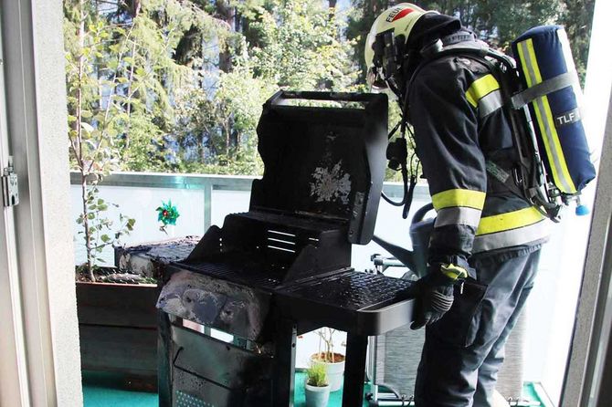 ein Feuerwehrmann der einen brennenden Grill gelöscht hat
