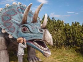 Kind mit Dinosaurier auf der Steinplatte in Waidring