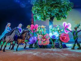 Märchenhaftes Bühnenbild mit Menschen, verkleidet als Blumen und Elfen auf Pferden