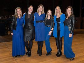 Sechs Frauen in blauer Kleidung, die für ein Foto posieren