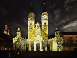 Kirchenfassade mit Lichtinszenierung vor Abendhimmel