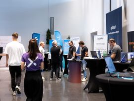 Besucher:innen informieren sich bei Ausstellerständen auf einer Veranstaltung von next:tirol.