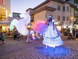 beleuchtete Pferdefiguren und eine Frau in einem weißen Kleid