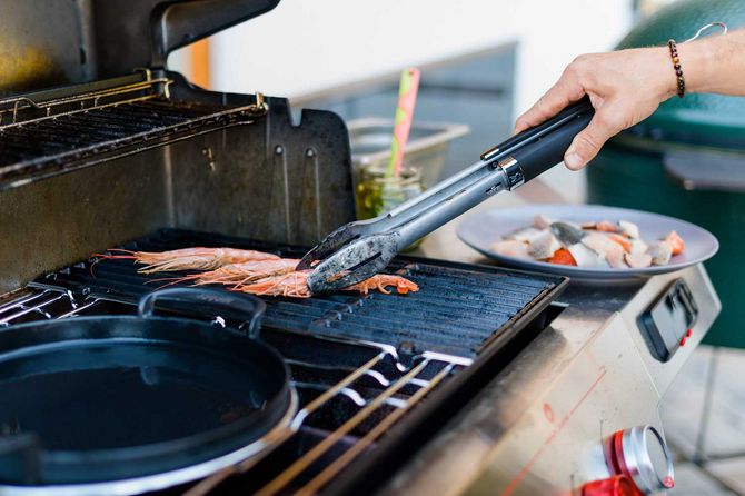 jemand grillt etwas und hält es mit der Grillzange