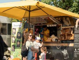 Frau uns zwei Kinder vor einem Essensstand