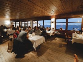 Gäste genießen ein Abendessen im Restaurant der Nordkette mit Blick auf die umliegende Berglandschaft.