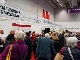 Besucher betrachten handgefertigte Dekorationen und Kunsthandwerk an einem Marktstand.