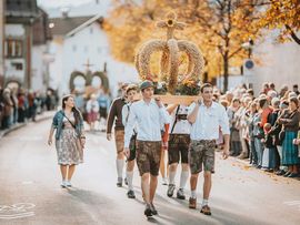 Jungbauern mit Krone aus Heu beim Erntedankfest in Reutte