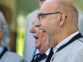 Sängerinnen und Sänger treten vor einem Gasthaus auf.