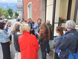 mehrere Menschen hören im Freien einem Mann zu