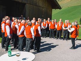 Singender Chor vor einer Almhütte