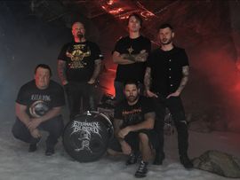 Fünf Musiker der Metal-Band Eternally Blinded posieren in einer felsigen Höhle vor roter Beleuchtung und ihrem Schlagzeug.