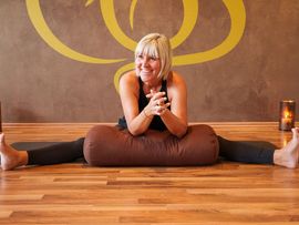 Yoga-Lehrerin auf Boden in Yoga-Pose mit Sitzsack