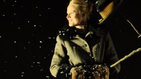 Junge Frau in Wintermantel vor schwarzem Hintergrund blickt aus dem Bild