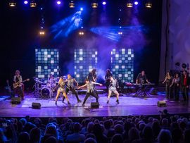 mehrere Schauspieler tanzen auf einer Bühne