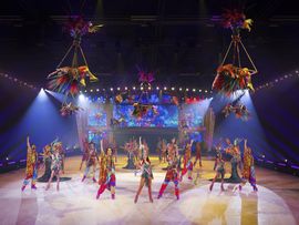 Eisläufer in bunten Kostümen vollführen eine Tanzperformance