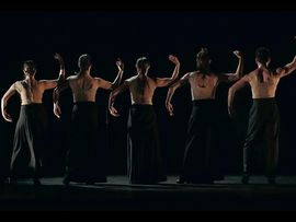 Mehrere Tänzer in gleicher Pose mit dem Rücken zu uns auf Bühne