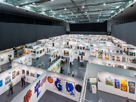 Blick über die weitläufige Ausstellungshalle der ART Innsbruck mit zahlreichen Messeständen.