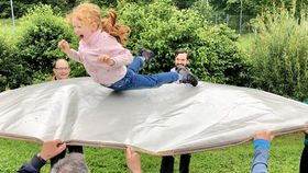 Mädchen wird von Männern auf einer Plane in die Luft geworfen