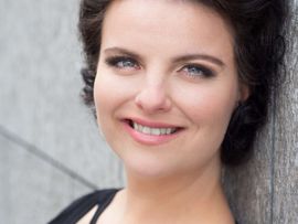 Frau mit dunklen Haaren schaut in die Kamera