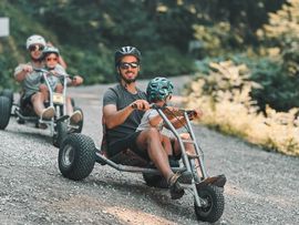 Vater und Kind fahren mit dem Mountain-Kart die Mutterer Alm runter.