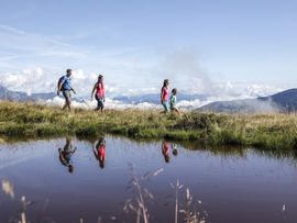 Wanderer neben Bergsee mit Alpenblick
