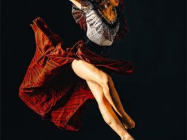 Tänzerin mitten im Sprung mit rotem Kleid