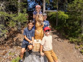 Sitzende Kinder mit Holzfigur auf der Rangger Alm