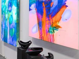 Ausstellungsstücke vor Leinwandgemälden auf der ART Innsbruck